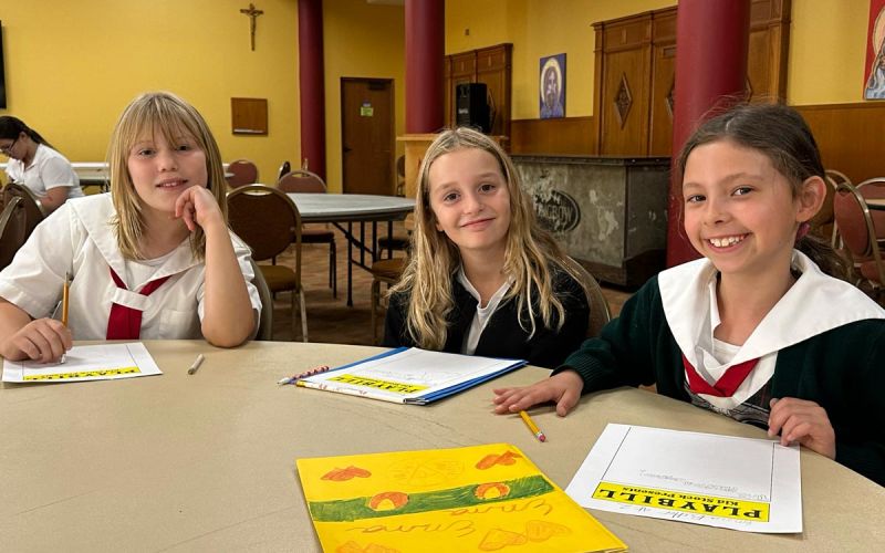 three girls working on playbills at art table